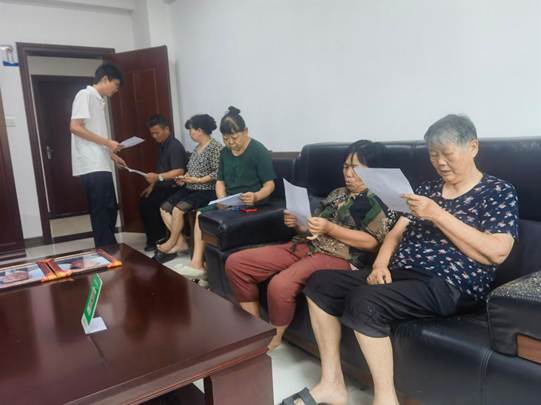 图为实践团成员向社区老人发放资助政策宣传手册